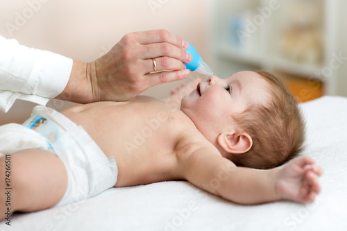 Fotografie woman hand cleans baby's nose with vacuum cleaner