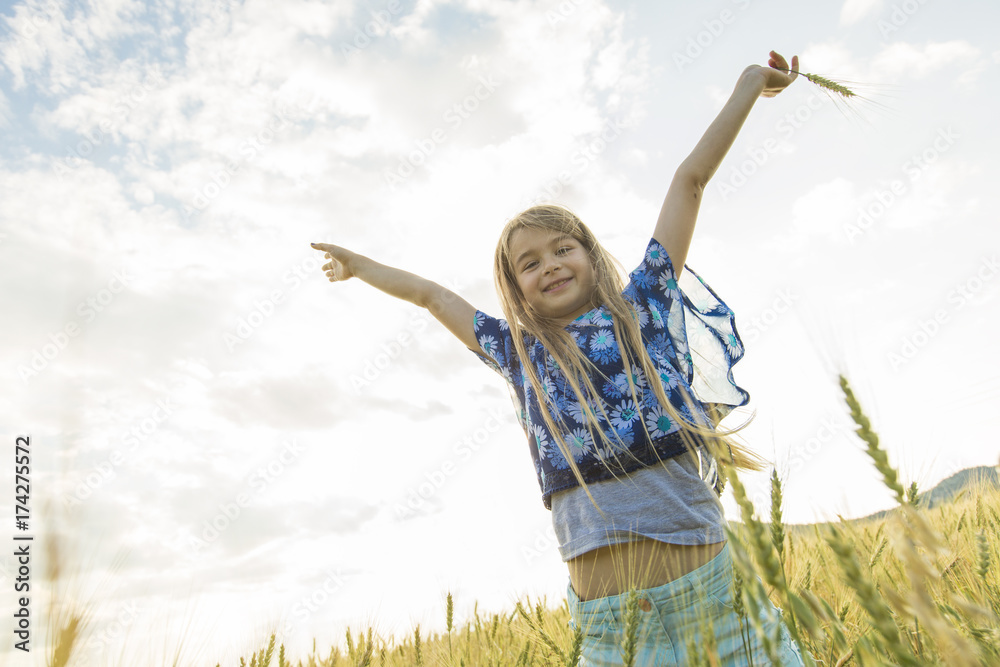 Adorable little girl playing in the wheat field on a warm summer day Adorable little girl playing in the wheat field on a warm summer day