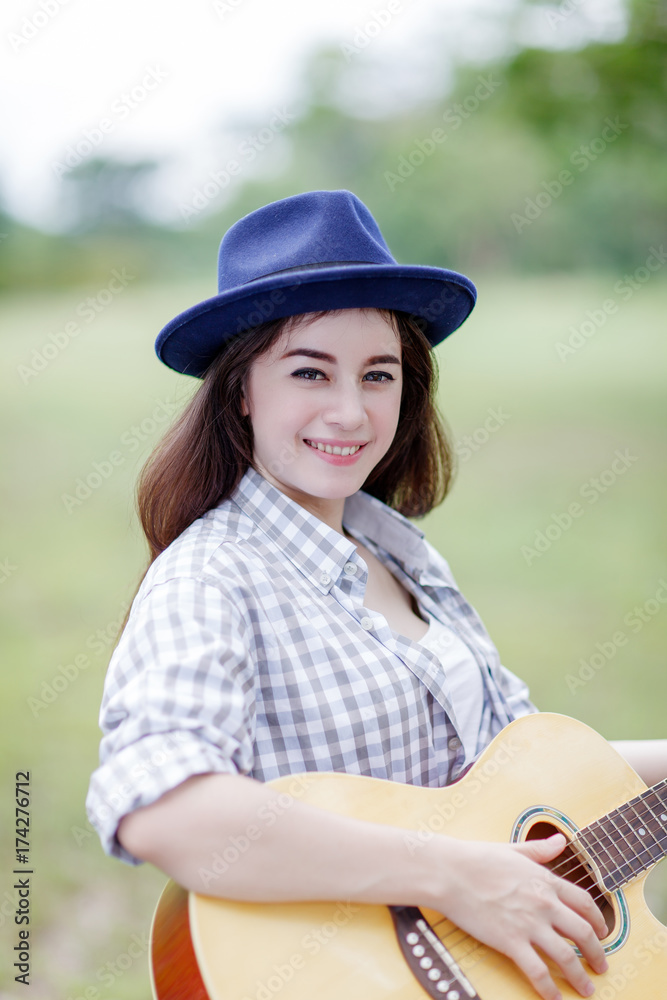 young woman playing guitar in the park