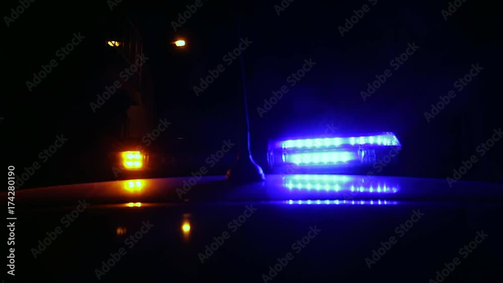 Luces Intermitentes de advertencia lanzando flash de colores en coche de la policia por la noche