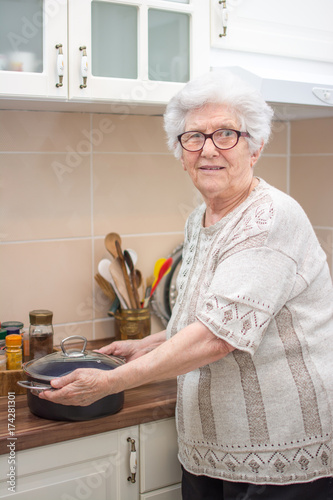 Senior woman holding cooking pot in the kitchen.