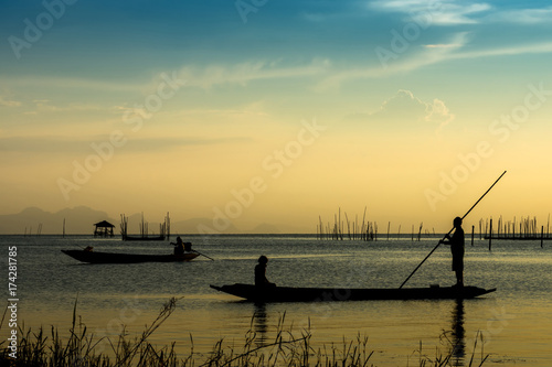 Fishermen and fishing boats float in the lake.