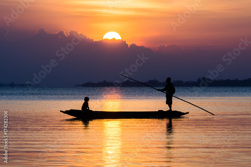 Fishermen and fishing boats float in the lake. © noppharat