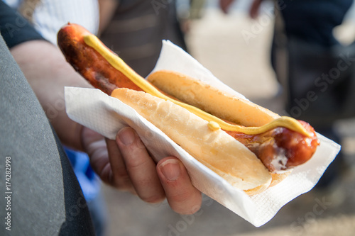 Männliche Hand mit Krakauer und Senf im Brötchen photo