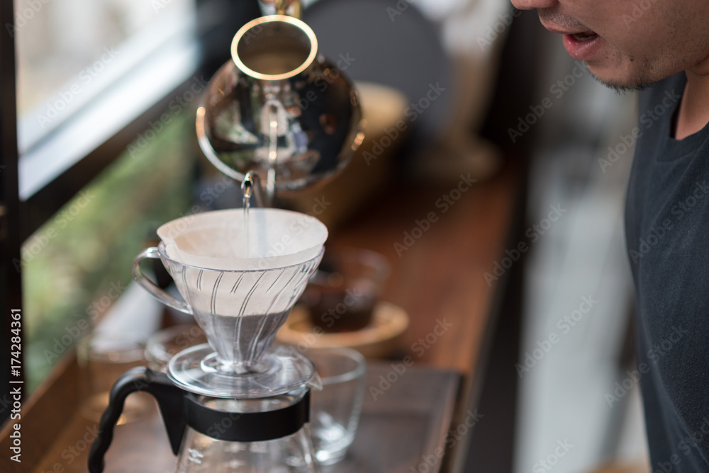 Barista pouring water on coffee ground with filter ; Hand drip coffee