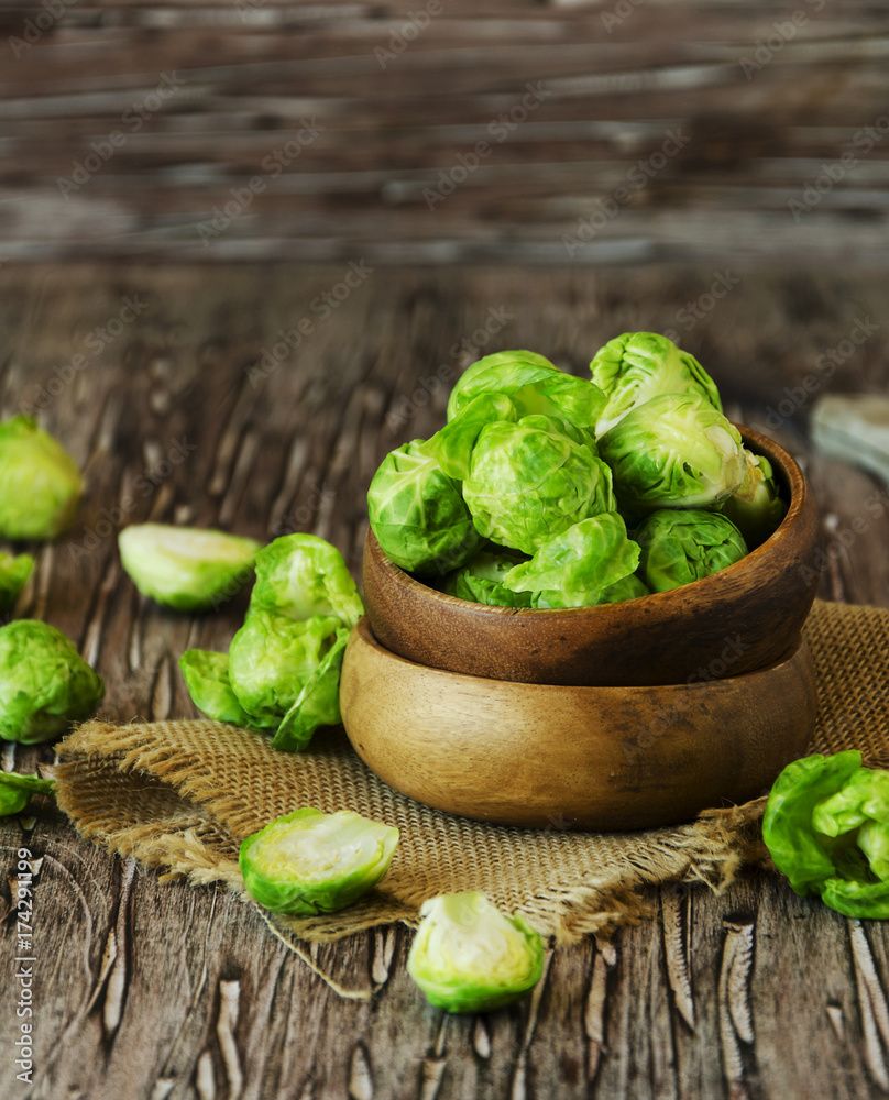 Green raw Brussels sprouts in wooden bowl , selective focus Green raw Brussels sprouts in wooden bowl , selective focus