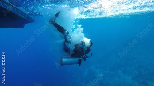 Underwater view of scuba diver backward roll entry into ocean from dive boat in Bunaken National Park, Sulawesi 