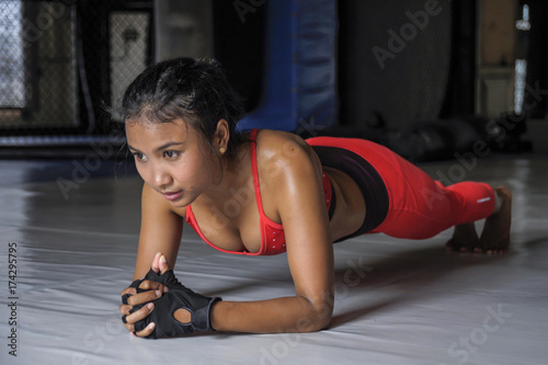sexy sweaty Asian woman in sport clothes lying on plank position on gym dojo floor in hard training fitness workout