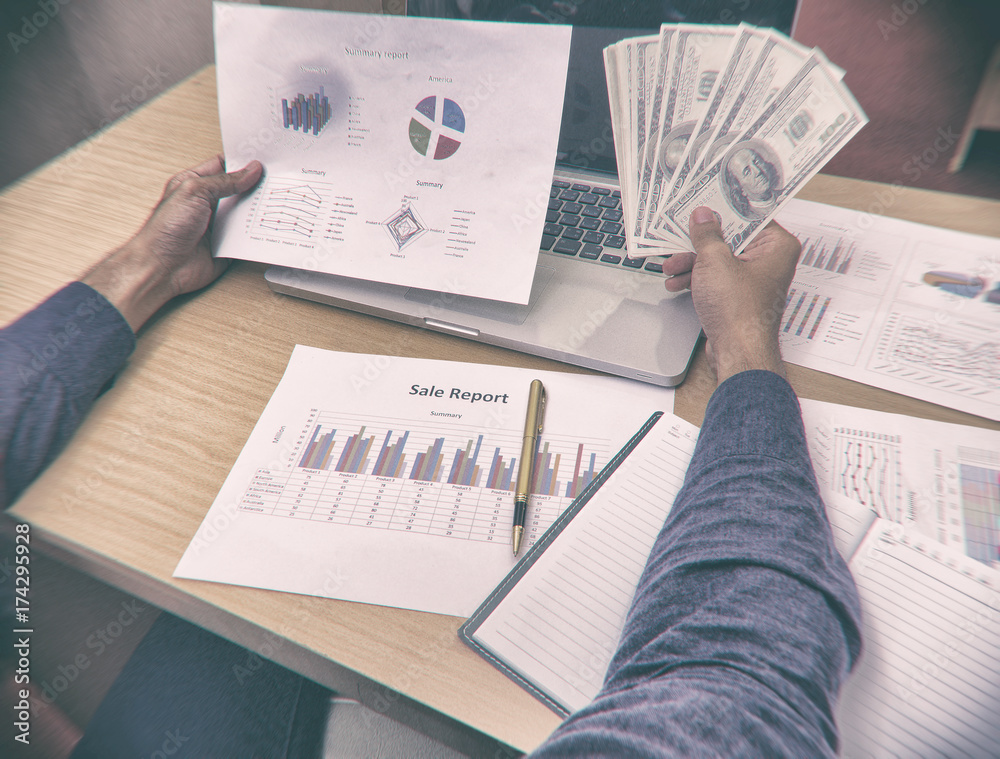 Naklejka premium The blurry design backgroud of paper investment chart and money,they were holding by business worker hand,dramatic tone,abstract art design,vintage art style,grainy film and classic old film style,