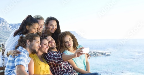 Friends taking group photo against blurry coastline
