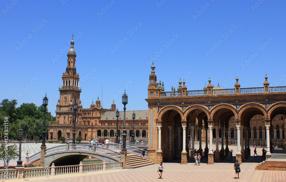 Historical Architecture of Plaza de Espana with beautiful Columns and Spanish Flag raised in Seville. Spain Square famous Andalusia travel attraction with no people on summer day, clear sky background