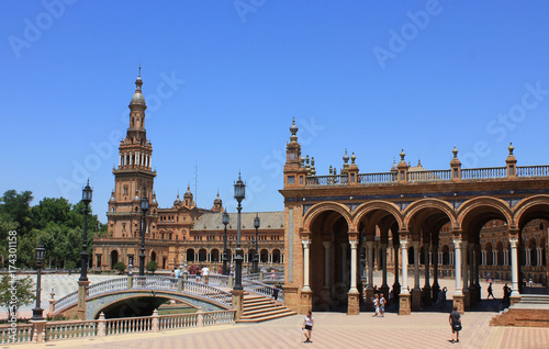 Historical Architecture of Plaza de Espana with beautiful Columns and Spanish Flag raised in Seville. Spain Square famous Andalusia travel attraction with no people on summer day  clear sky background