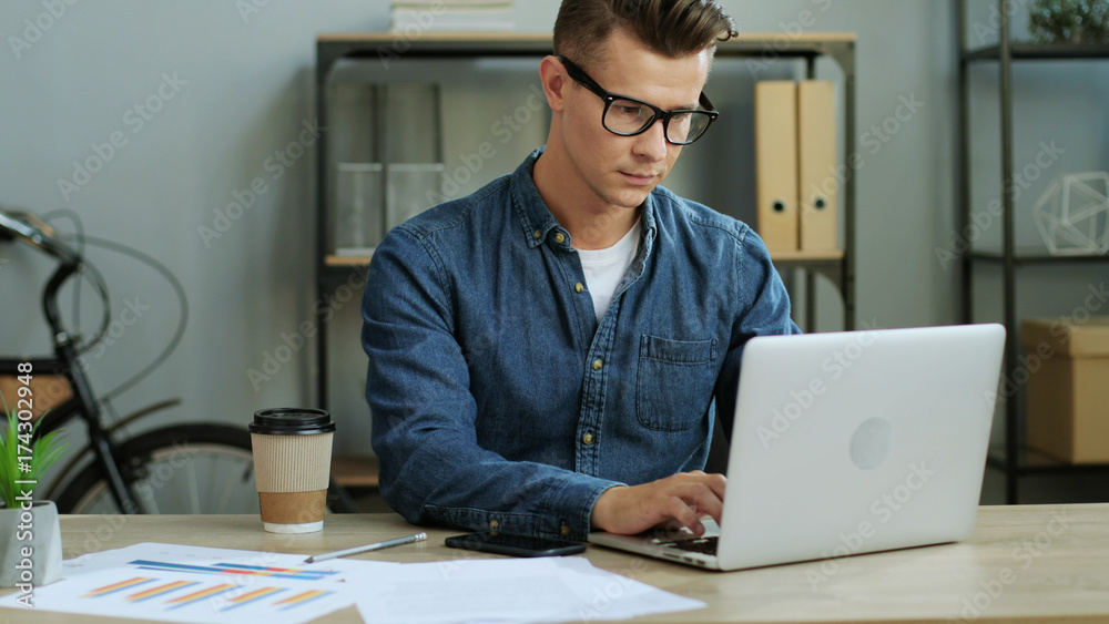 Young business man working in the modern office, using laptop and drinking the coffee. Young business man working in the modern office, using laptop and drinking the coffee.