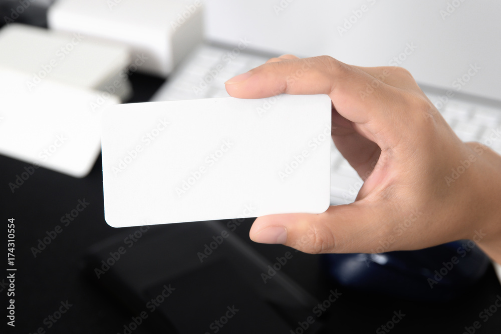 Blank business card mock up in hand on blurred office desk background use us contact information design templete Blank business card mock up in hand on blurred office desk background use us contact information design templete