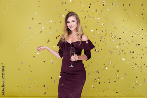 Happy New Year to you. One young and beautiful woman dancing with glass of champagne and smiling. Girl is happy about the New Year