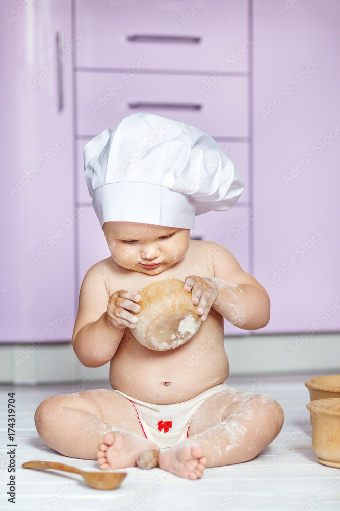 The little child is playing in the kitchen at the flour. Cook. The concept of childhood, upbringing, healthy food, family. The little child is playing in the kitchen at the flour. Cook. The concept of childhood, upbringing, healthy food, family.