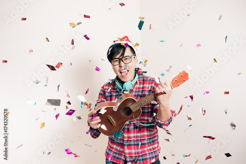 Happy Joyful Party Concept - One Asian People Holding Ukulele Having Fun and Enjoy with Colorful Confetti in Club