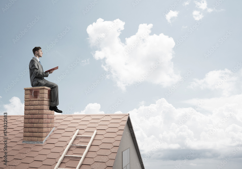 Student guy in suit on brick house roof reading book Student guy in suit on brick house roof reading book