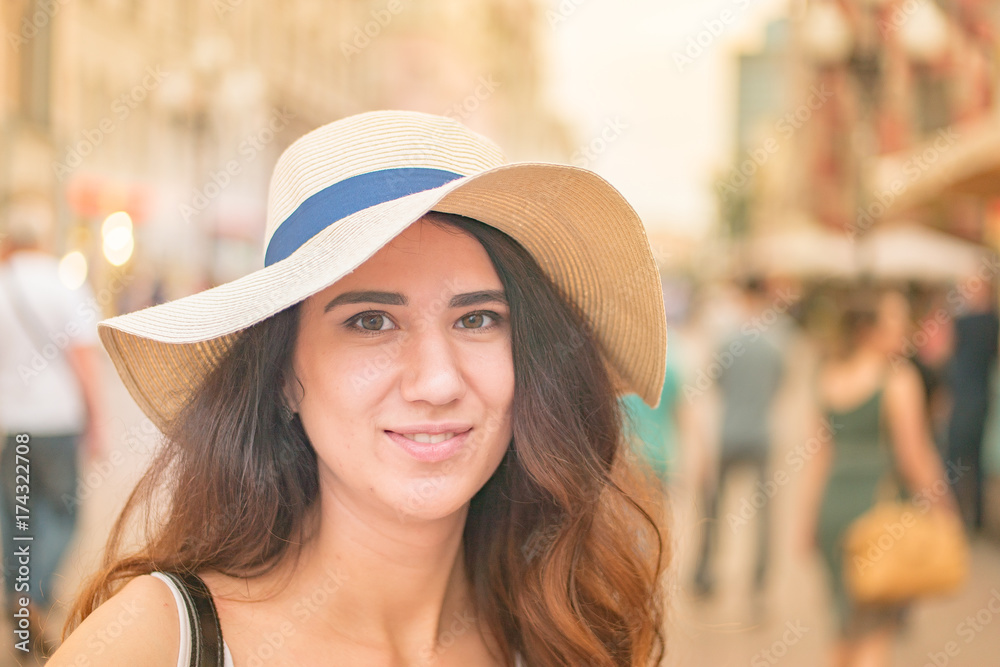 Girl with hat on summer day in the street. Happy smiling face.