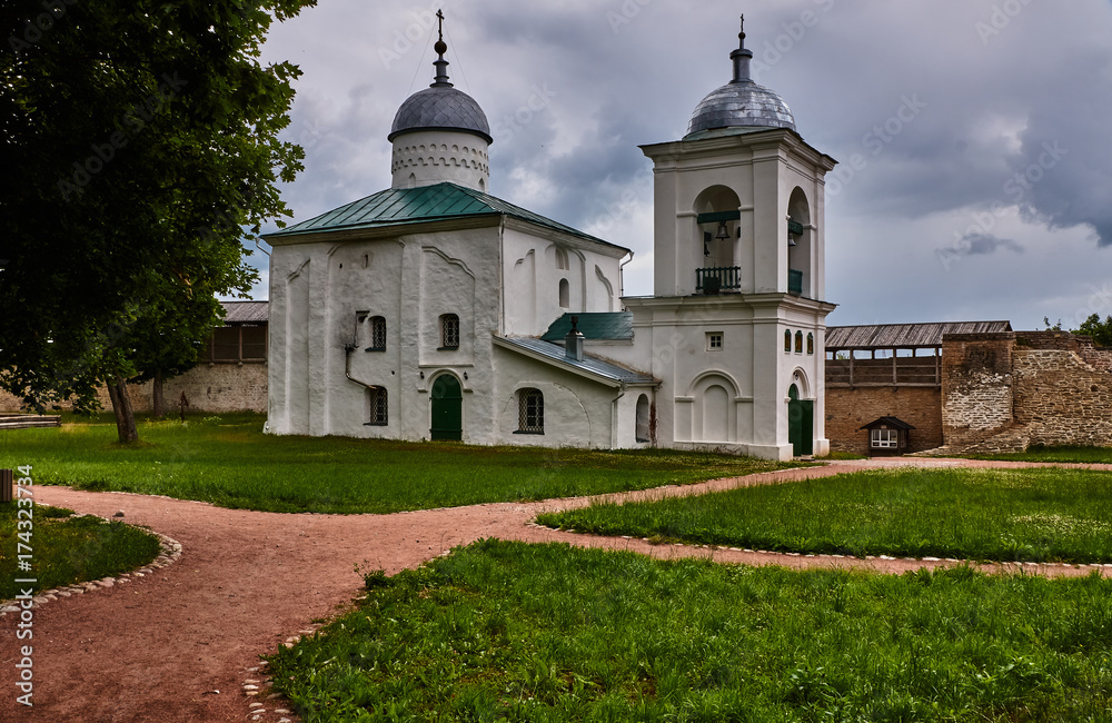 Orthodox church inside the fortress/The Orthodox temple is located inside the ancient fortress. Near the church there is a white one-tiered bell tower. Russia, Pskov region, landscape