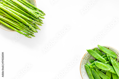 Fresh green pea pods and sprout of asparagus on white background top view copyspace