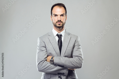 Business young man looking at camera over gray background.