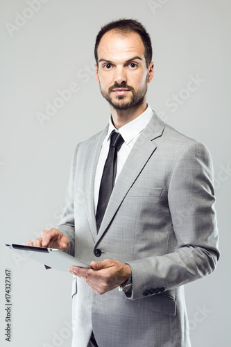 Business young man using his digital tablet over gray background.