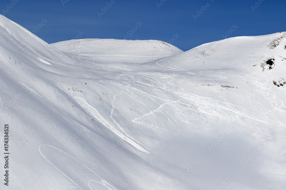 Snow off-piste slope with traces of skis, snowboards and avalanches
