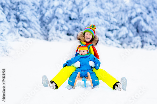 Mother and baby on sleigh ride. Winter snow fun.