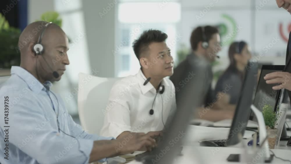 Customer service ops taking calls in busy call center with manager overseeing Customer service ops taking calls in busy call center with manager overseeing