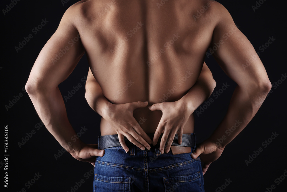 Female hands touching body of sporty young man on dark background Stock  Photo