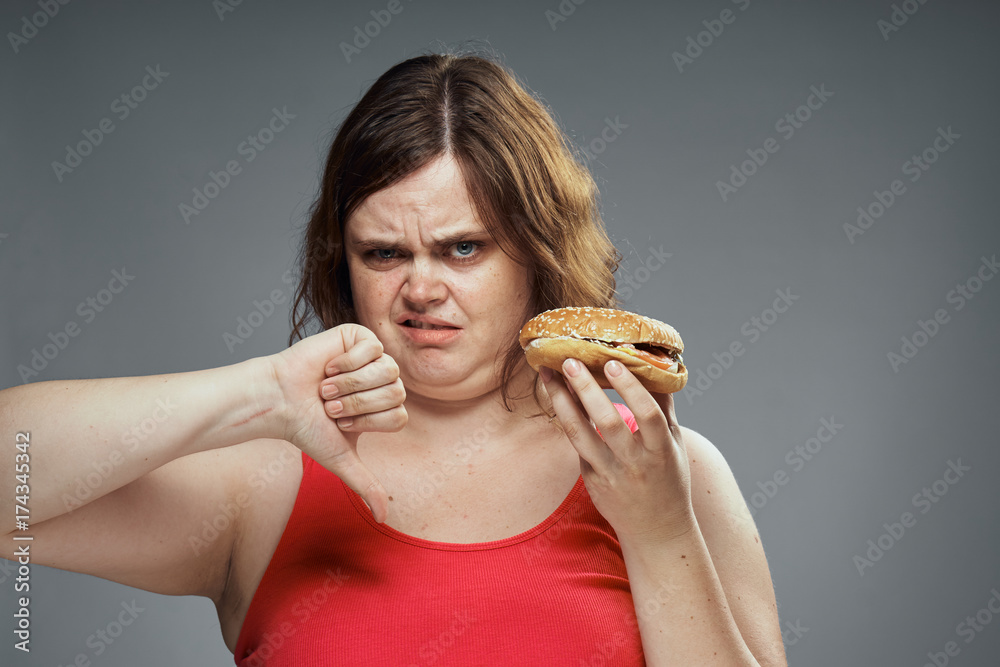 fat woman holding a hamburger, portrait, finger down fat woman holding a hamburger, portrait, finger down