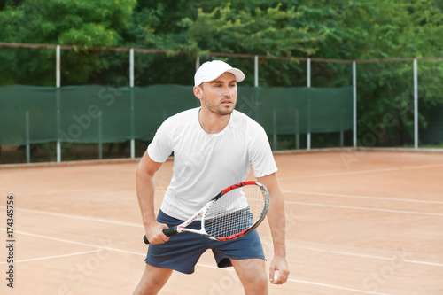 Young man playing tennis on court © Africa Studio