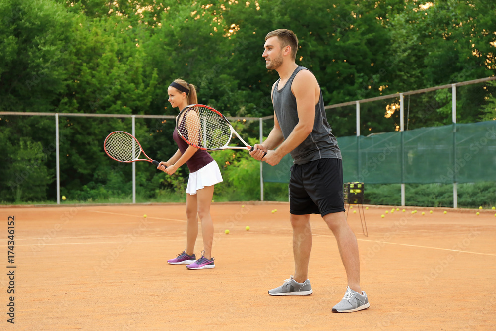 Young man and woman playing tennis on court