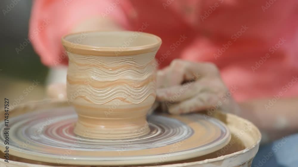Homemade pottery from clay Female potter craftsman helps the learner to work on pottery wheel