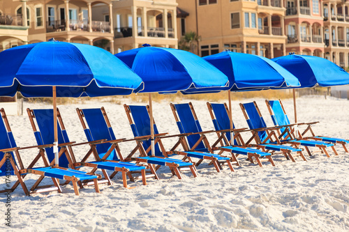 Row of blue lounge chairs and umbrellas on a white sand beach in Dustin Florid photo