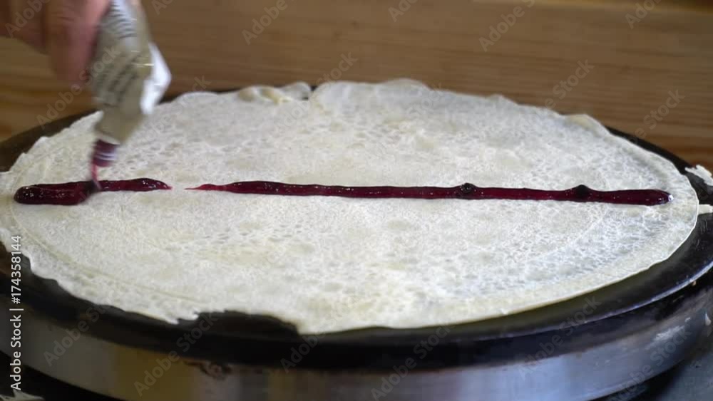 The chef smears jam on a hot thin pancake. Sweet, delicious pancake. Close up The chef smears jam on a hot thin pancake. Sweet, delicious pancake. Close up