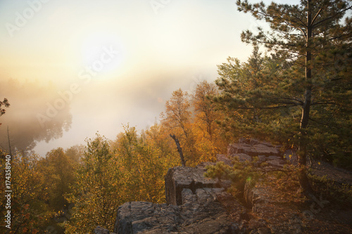 Granite cliff and pines overlooking misty lake in northern Minnesota boundary waters