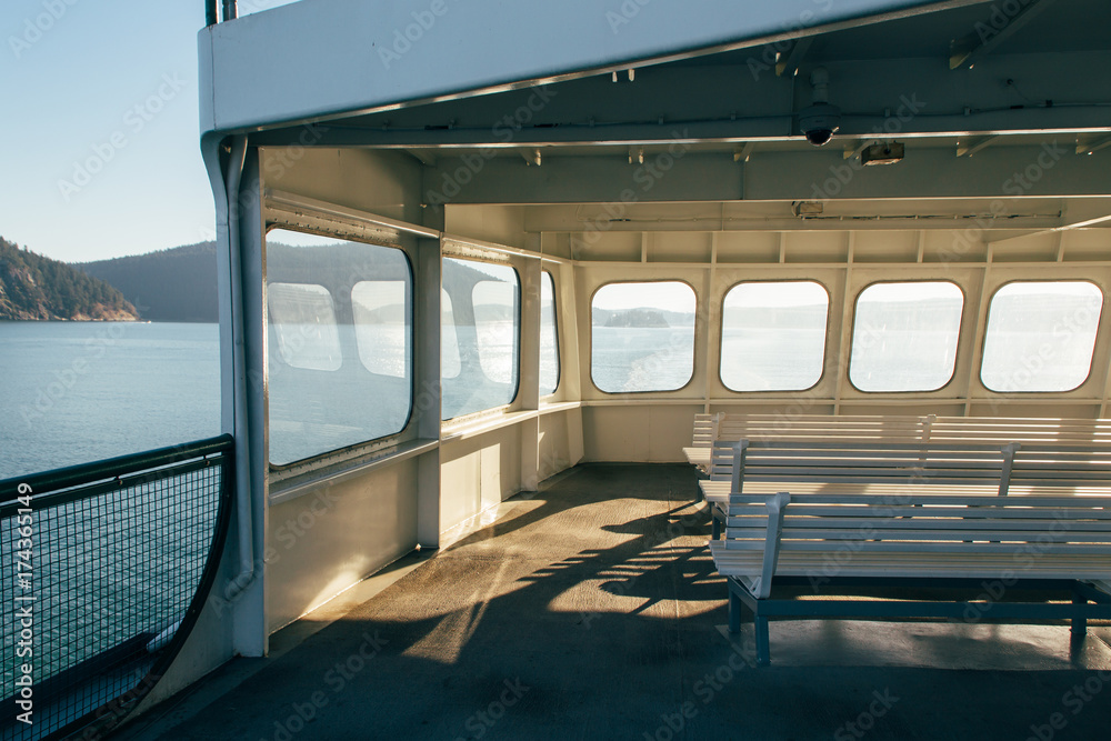 © Luke Mattson/Stocksy - Windows Glowing With Sunlight On Upper Deck of Passenger Ferry Boat