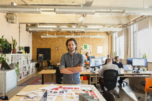 Young designer standing in his office, looking at the camera photo