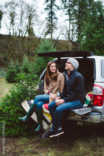 Couple sitting on the tailgate of a truck after cutting down their Christmas tree. photo