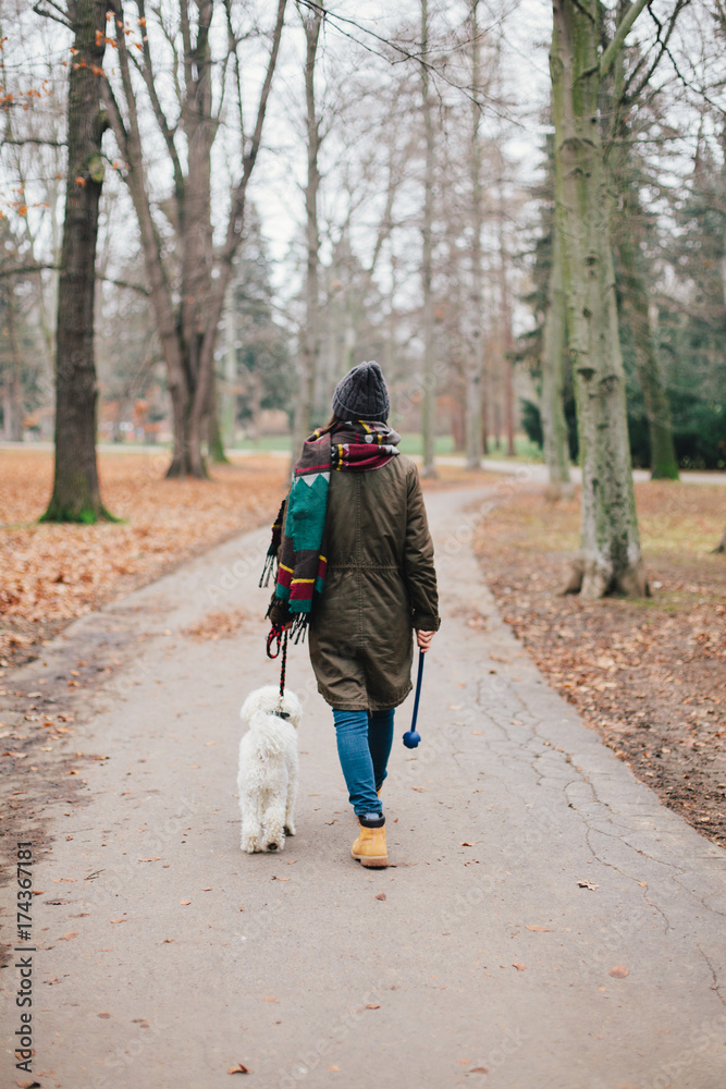 Woman walking her dog through the park Woman walking her dog through the park