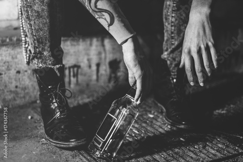 hangover,drunk person in jeans and boots on the street,addict, bottle of alcohol drink photo