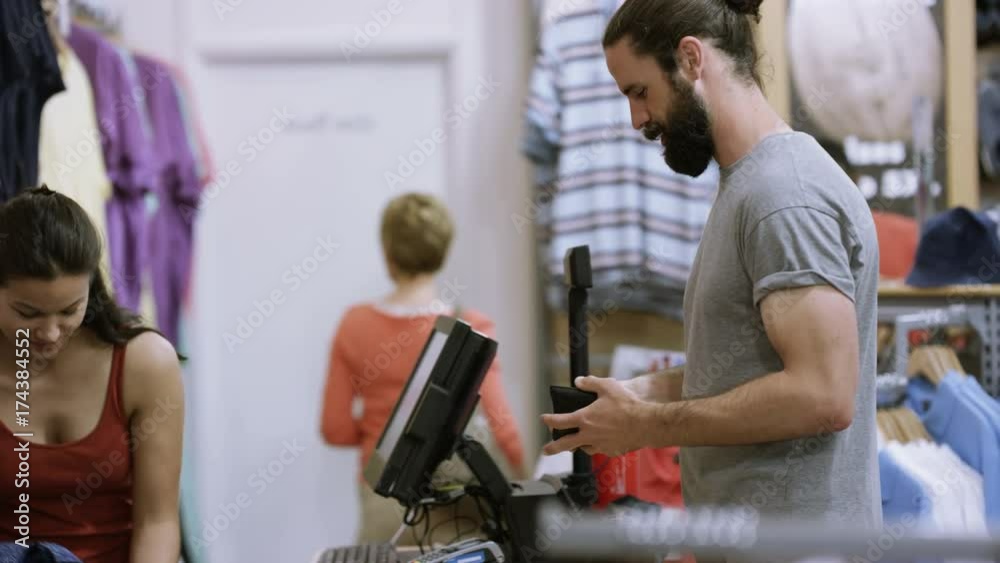 Customer in clothing store paying for a purchase with his credit card Customer in clothing store paying for a purchase with his credit card