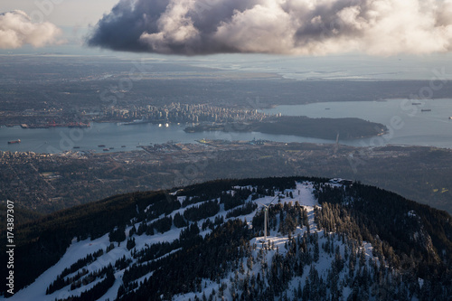 Aerial view of Grouse Mountain and Vancouver Downtown City  BC  Canada  in the background. Picture taken during a cloudy winter sunset.