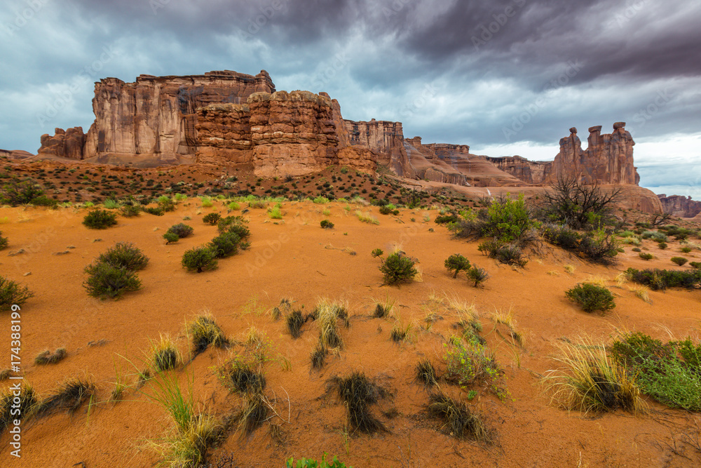 Dramatic storm clouds, rain, and red sandstone formations in the Arches National Park, Utah