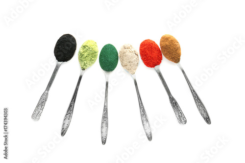 Different colorful superfood powders in spoons on white background