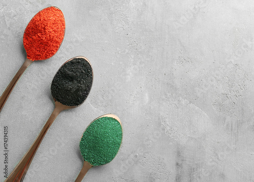 Different colorful superfood powders in spoons on table