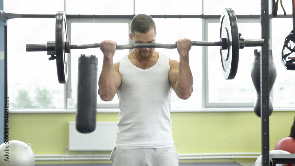 athlete doing exercise for biceps with barbell. young muscular man trains at the gym athlete doing exercise for biceps with barbell. young muscular man trains at the gym