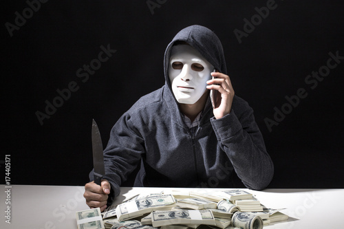 Man wearing white mask with a knife call someone to get money. isolated on black background photo
